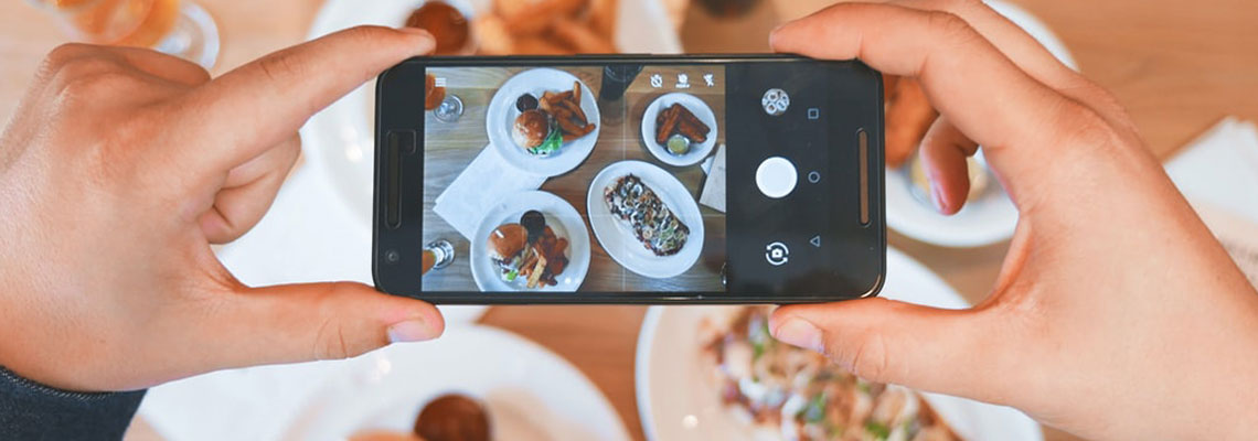 Photo d'un influenceur food qui prend son plat en photo avec son téléphone